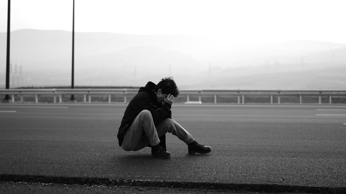 Person hunched over on an empty road